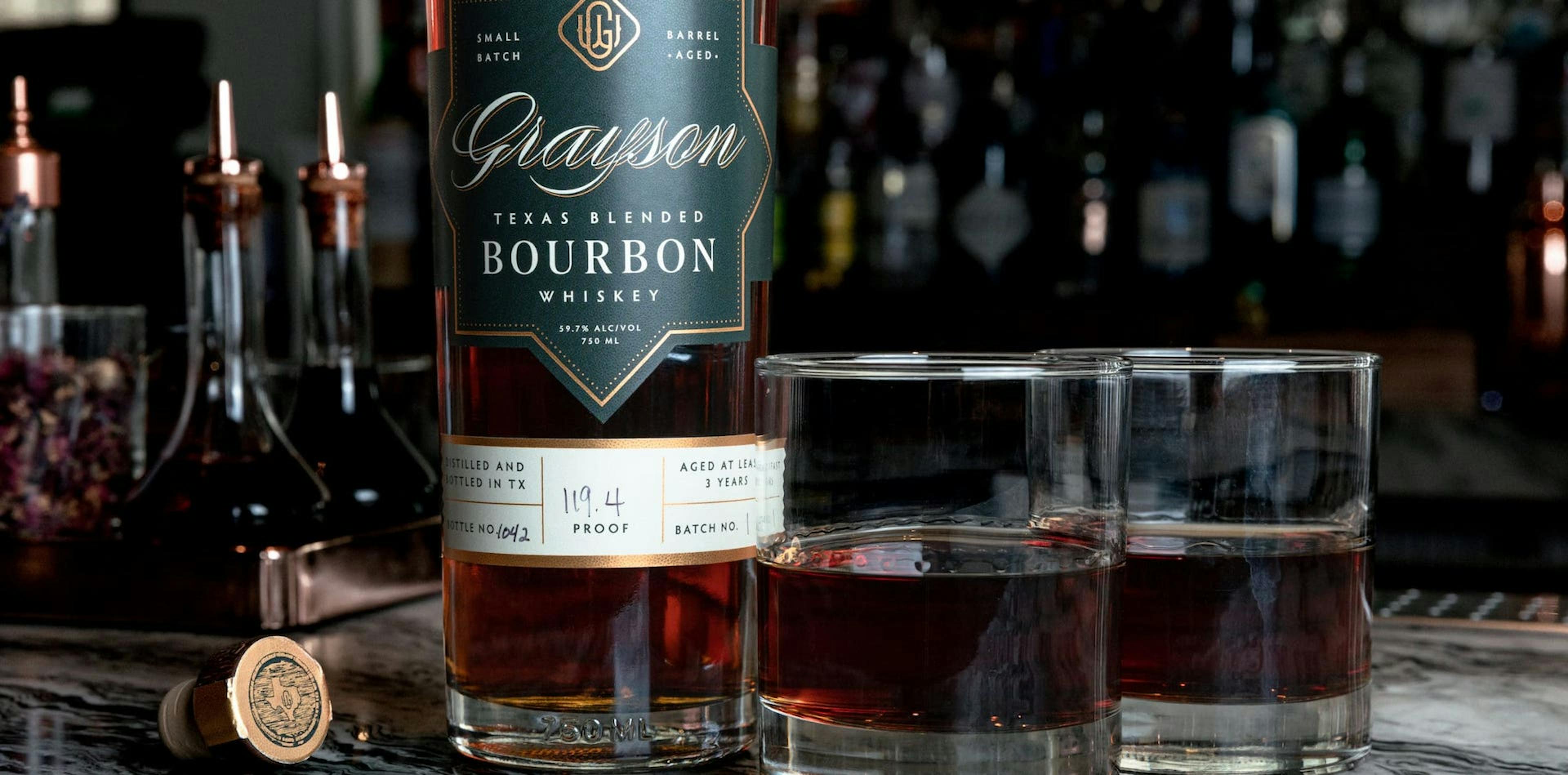 Grayson Whiskey bottle with two glasses of whiskey on bar top