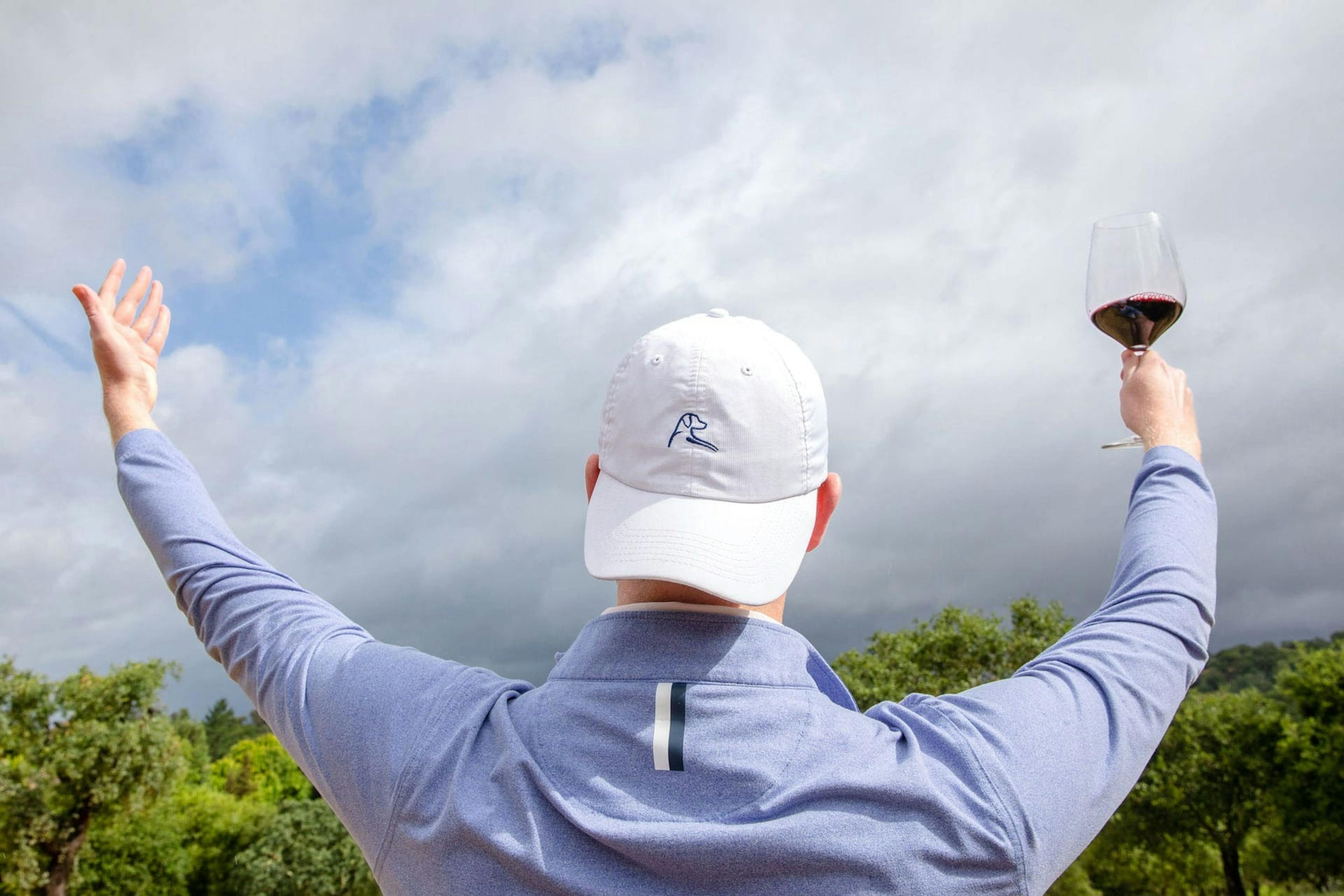 Man admiring view wearing a Rhoback hat drinking Two Old Dogs wine