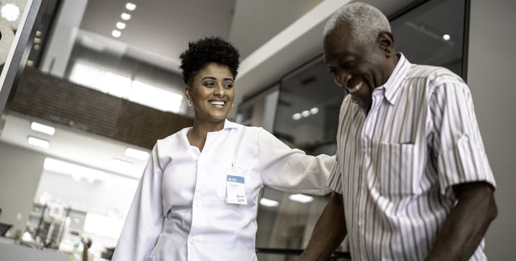 médica sorrindo ajudando paciente a caminhar
