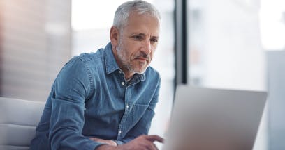 Senhor sentado de frente ao computador.