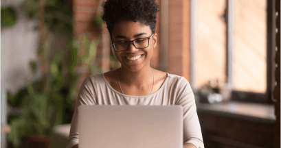 Mulher sorrindo digitando no notebook.