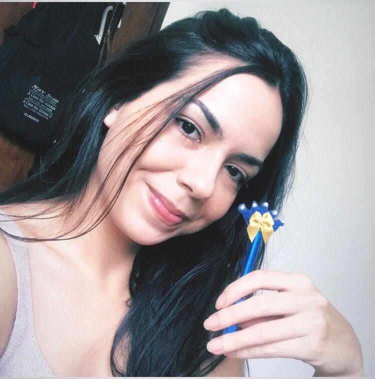 Jovem segurando uma caneta azul contendo uma coroa.