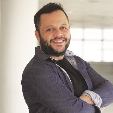 Homem sorridente de braços cruzado.