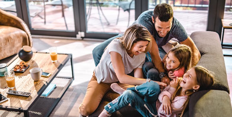 família brincando de cócegas no sofá