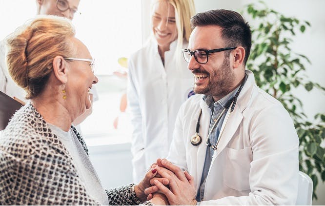 Médico segurando a mão de uma idosa