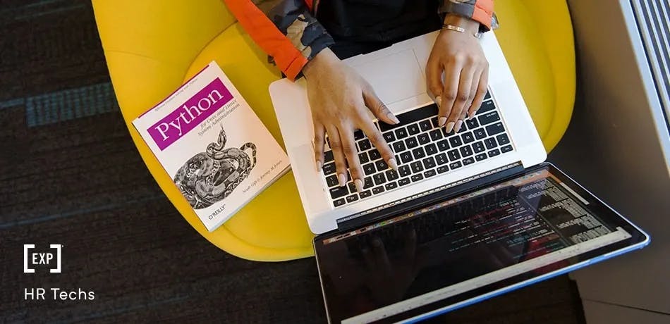 Desenvolvedor escrevendo em seu laptop com um livro de Python ao lado