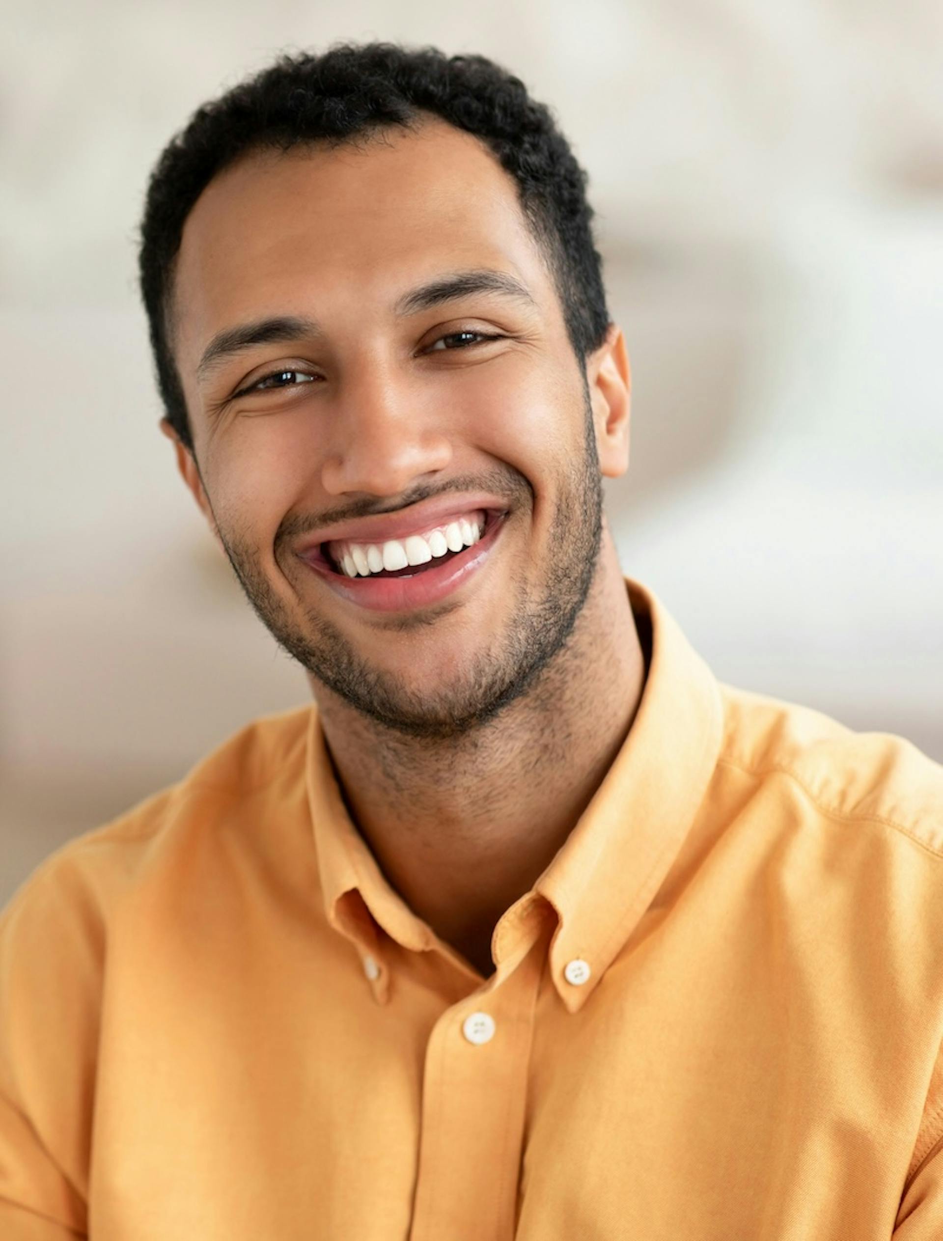  Smiling tutor in a yellow shirt, representing approachable and professional tutoring services.