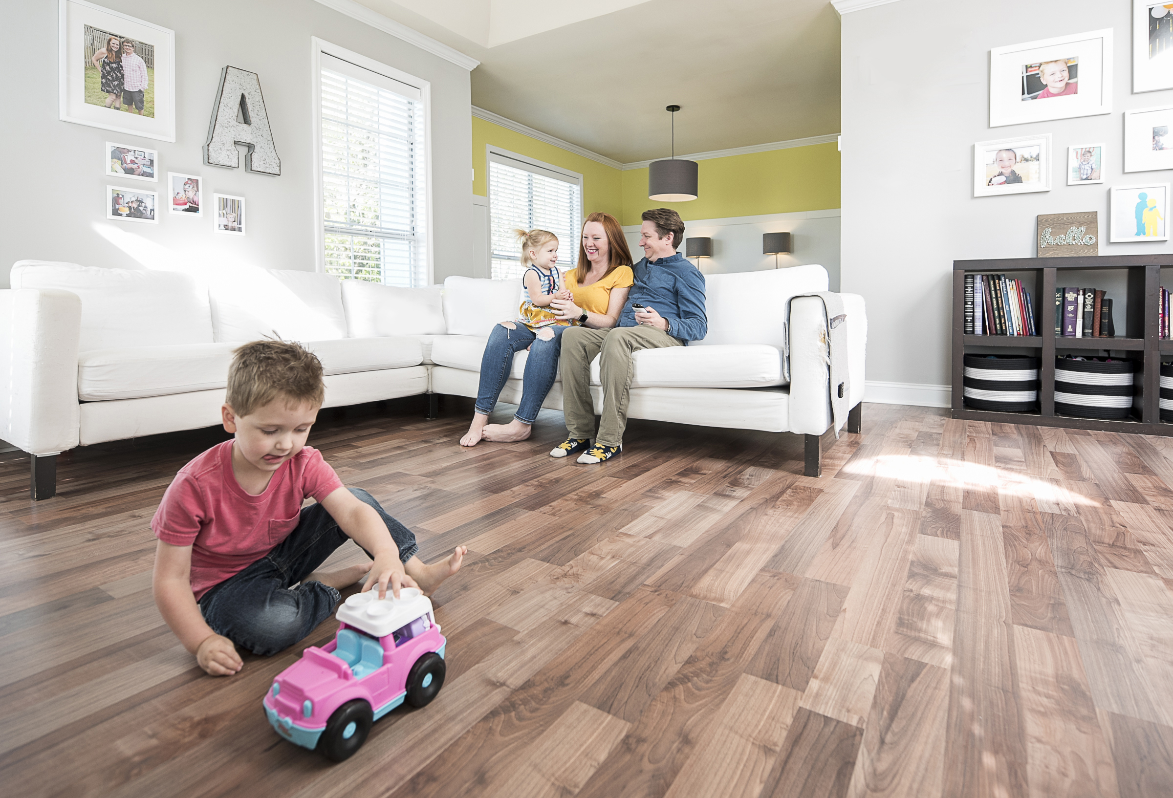 child playing in foreground, parents on white couch in background