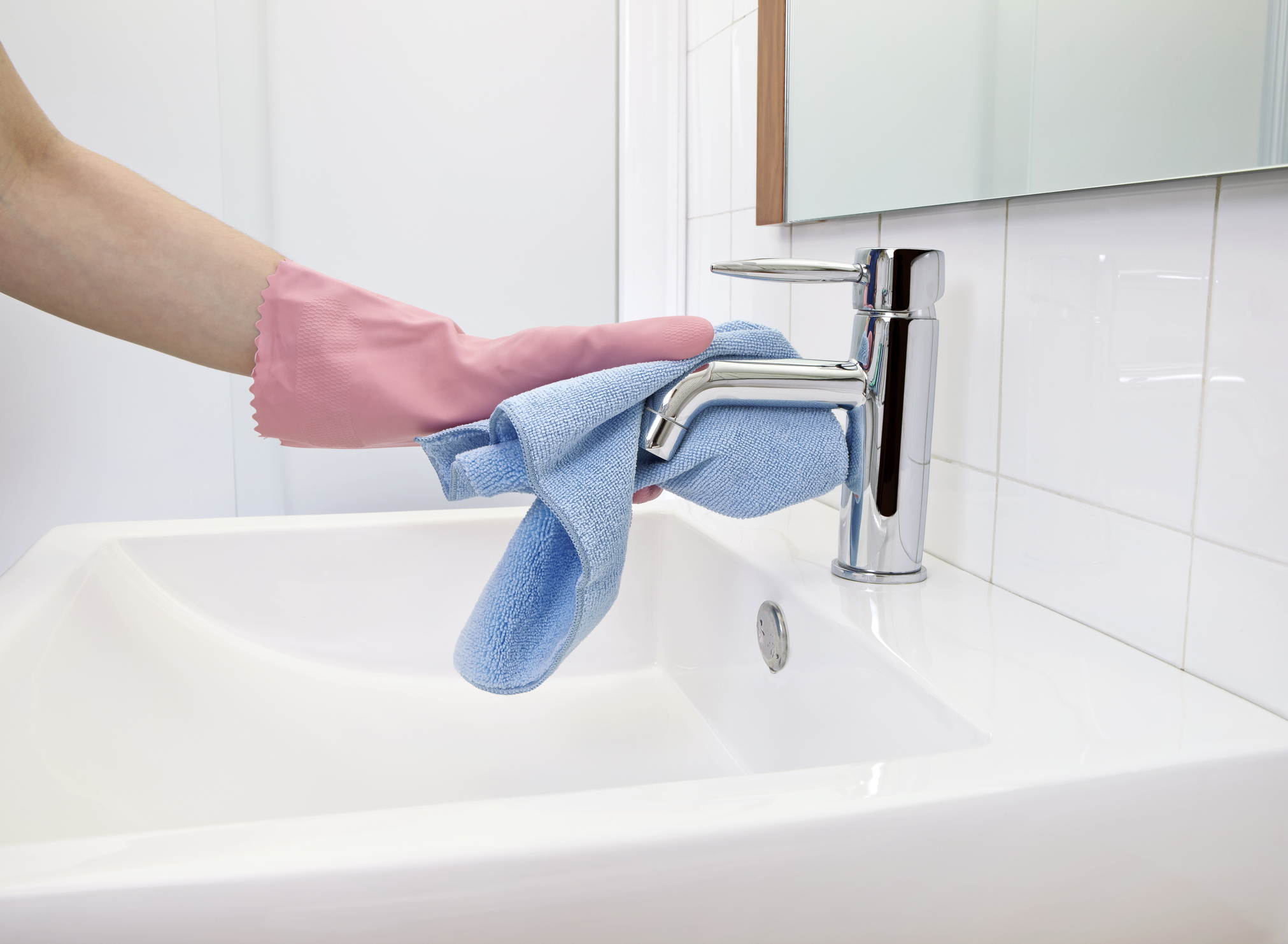 person with glove on cleaning bathroom sink