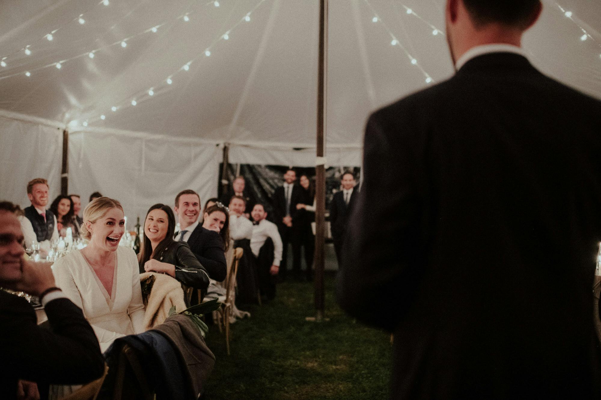 bride candidly laughing at her husband's speech
