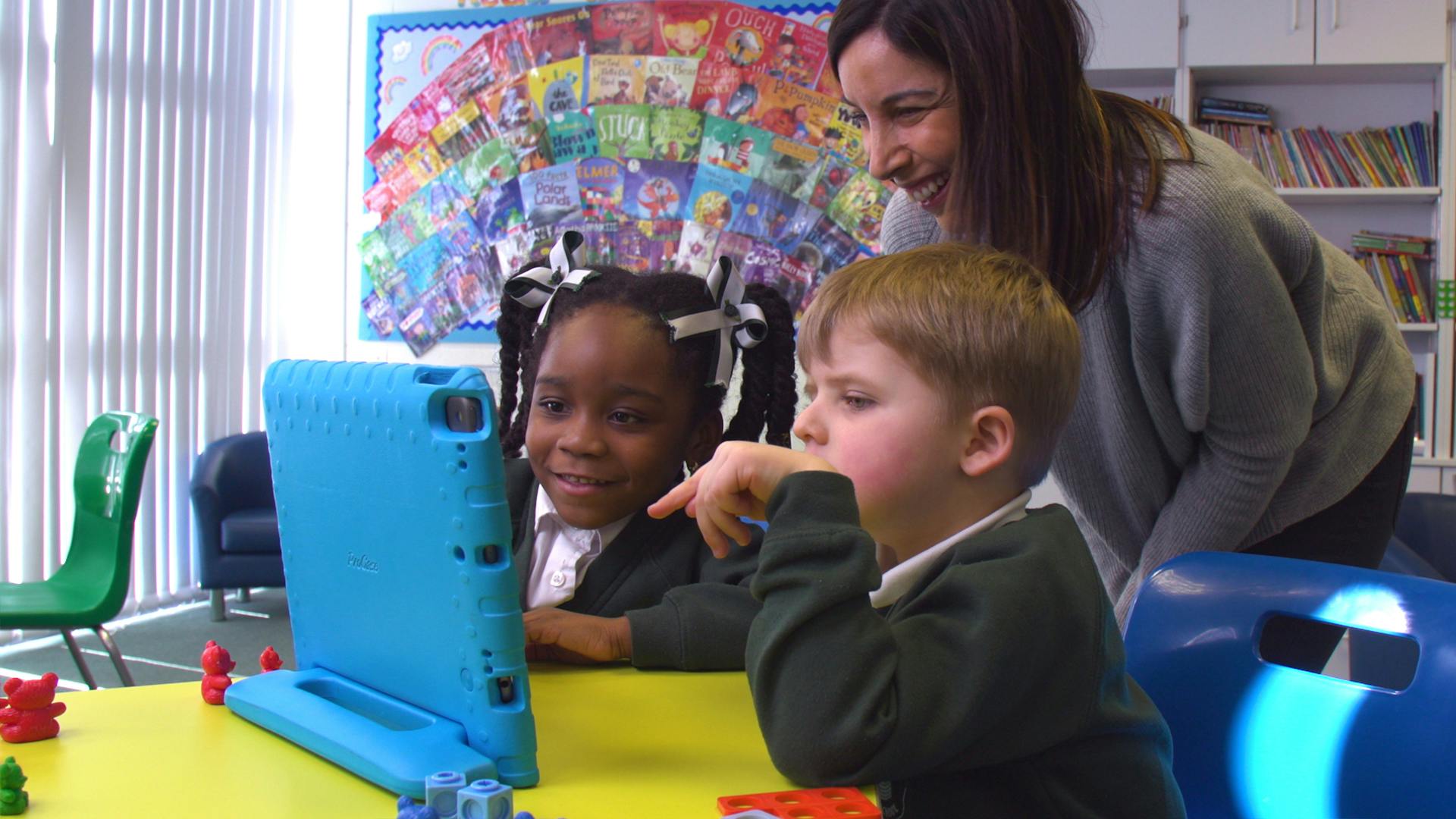 A teacher and pupils enjoy playing Teach Your Monster Number Skills together in a classroom.