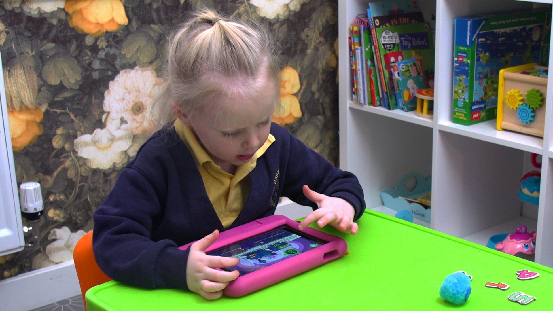 A child plays Teach Your Monster Number Skills on her tablet.
