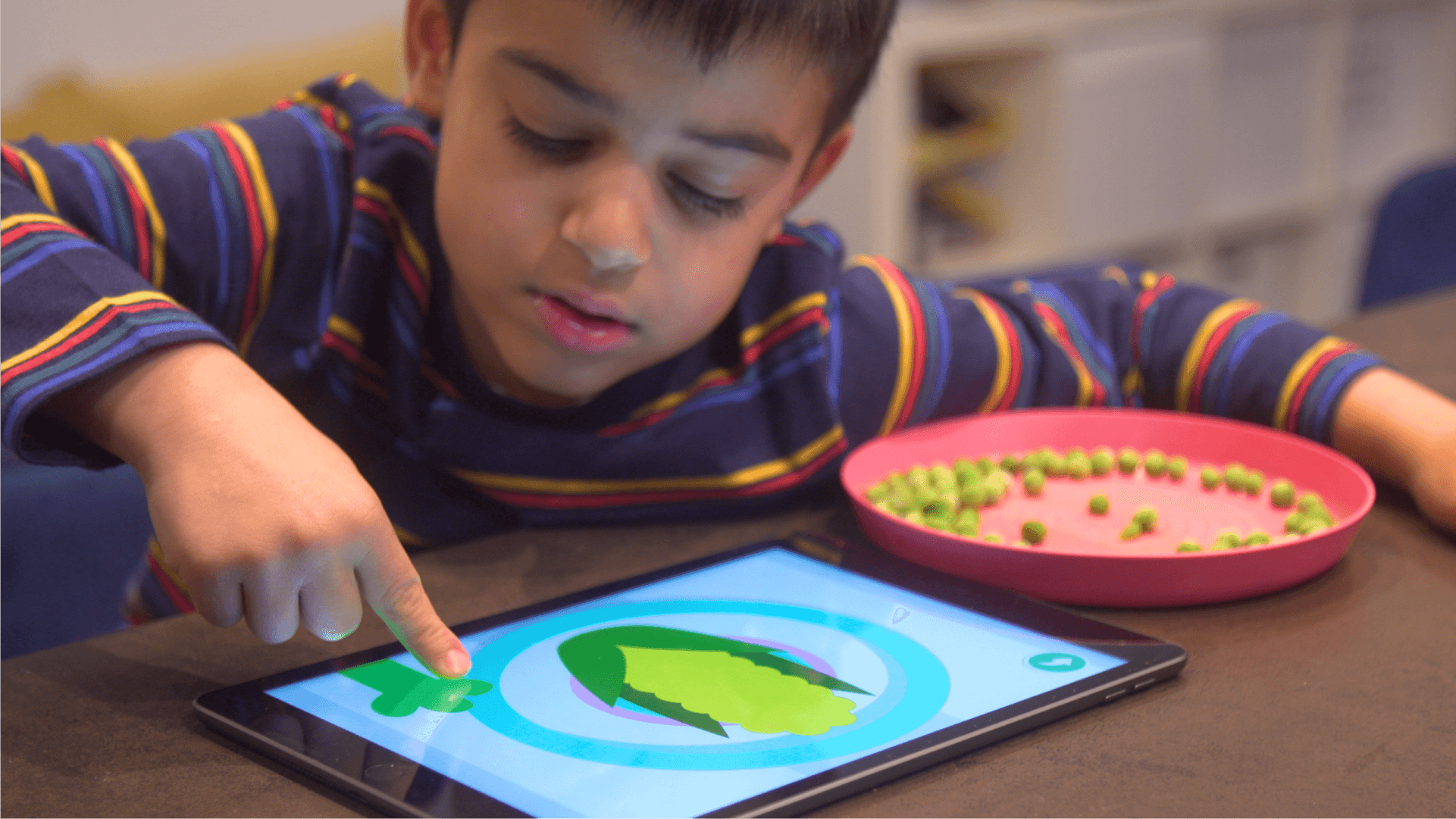 A child plays Teach Your Monster Adventurous Eating on his tablet.