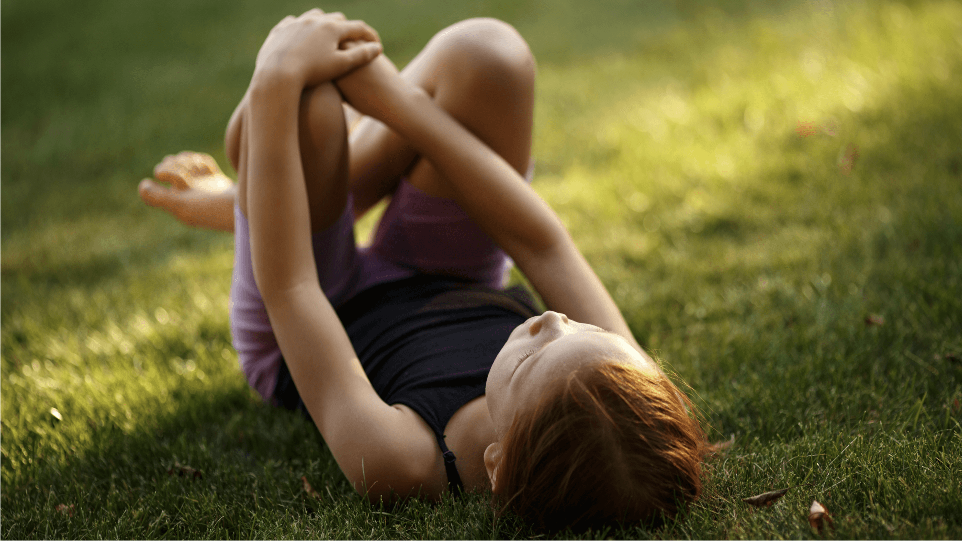 A child resting in the grass looking up at the sky 