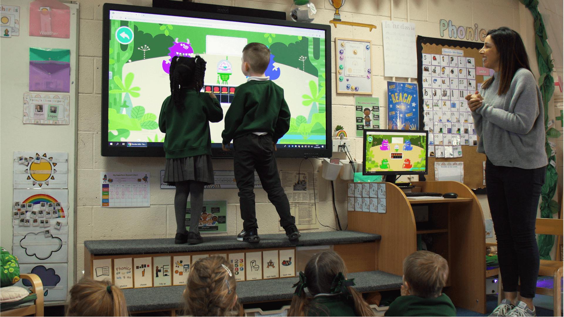 Carla observing two schoolchildren playing on the interactive whiteboard