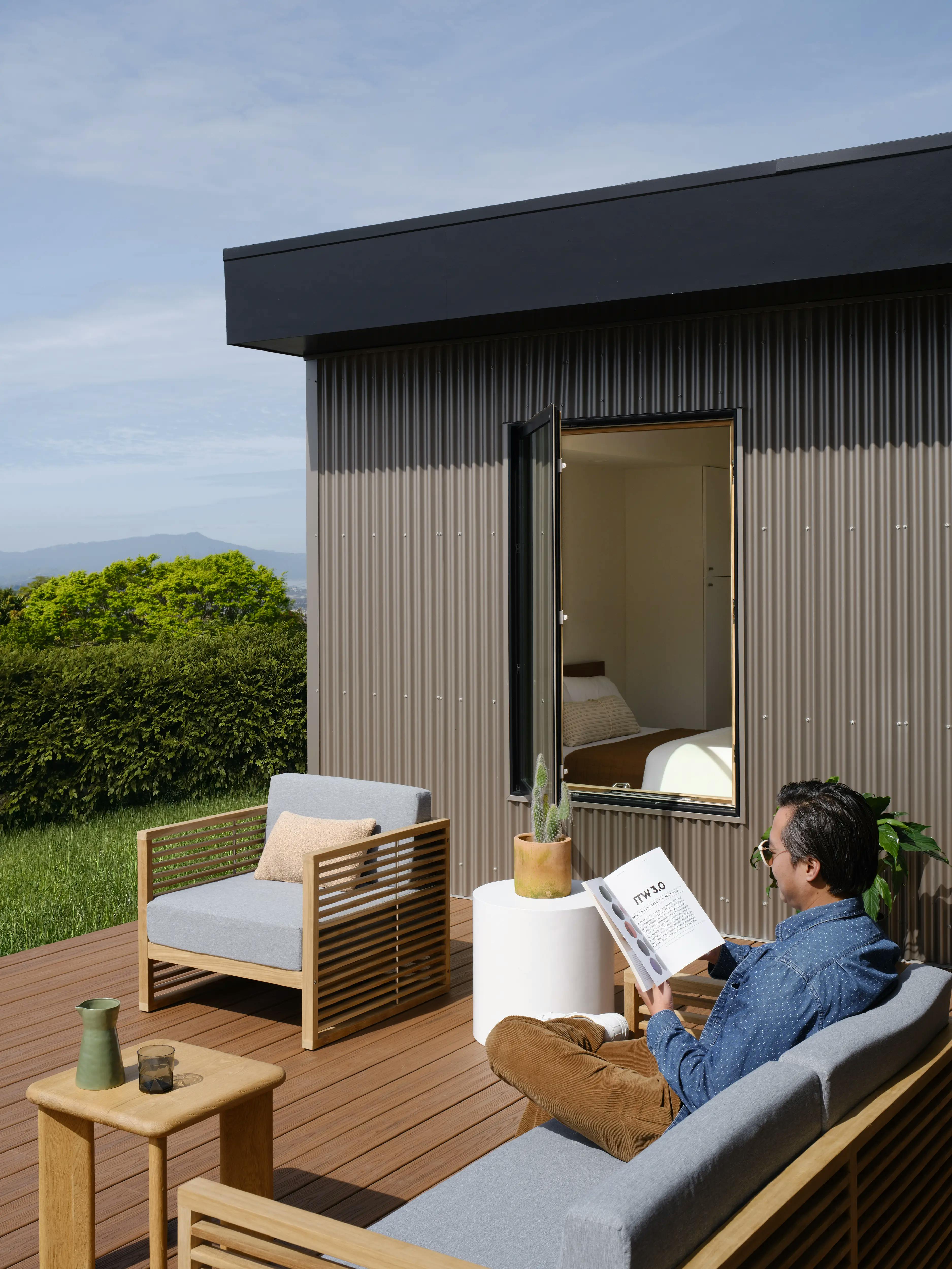 Exterior shot of a man reading a magazine on the deck of a Type Five ADU home