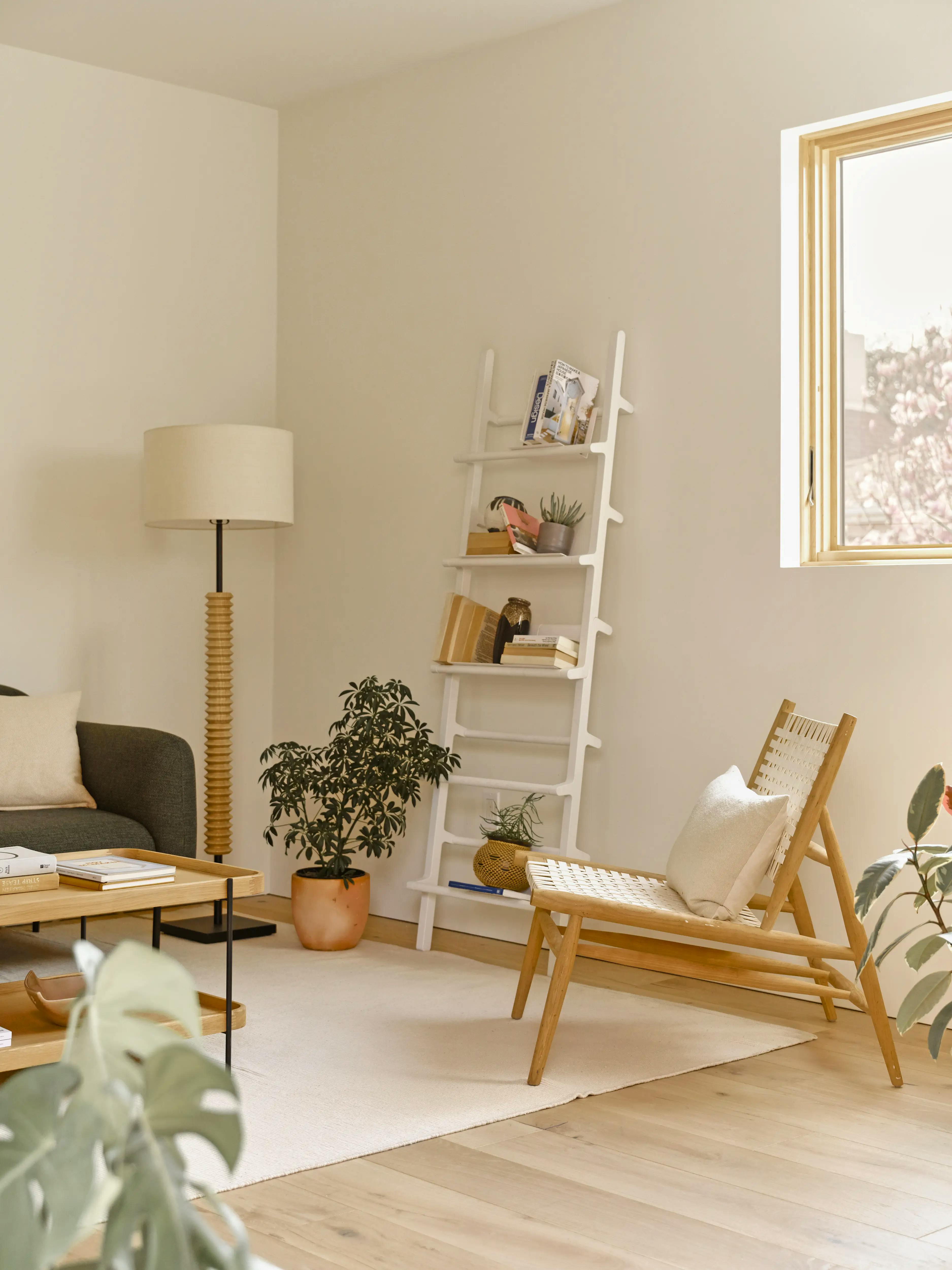 Interior shot of a living room in a Type Five ADU, staged with an armchair and leaning ladder shelf
