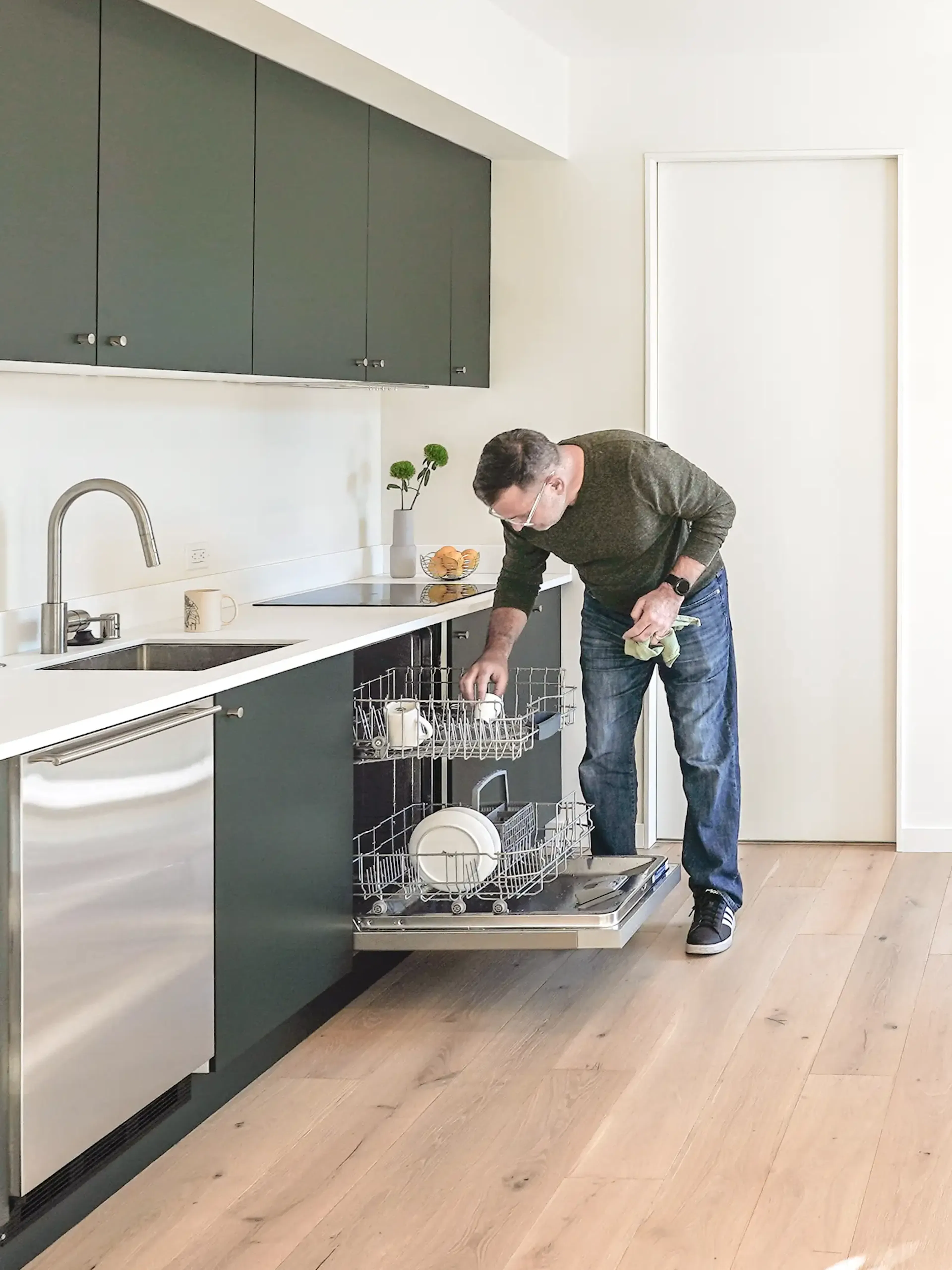 Interior view of a Type Five ADU kitchen with the homeowner loading the dishwasher
