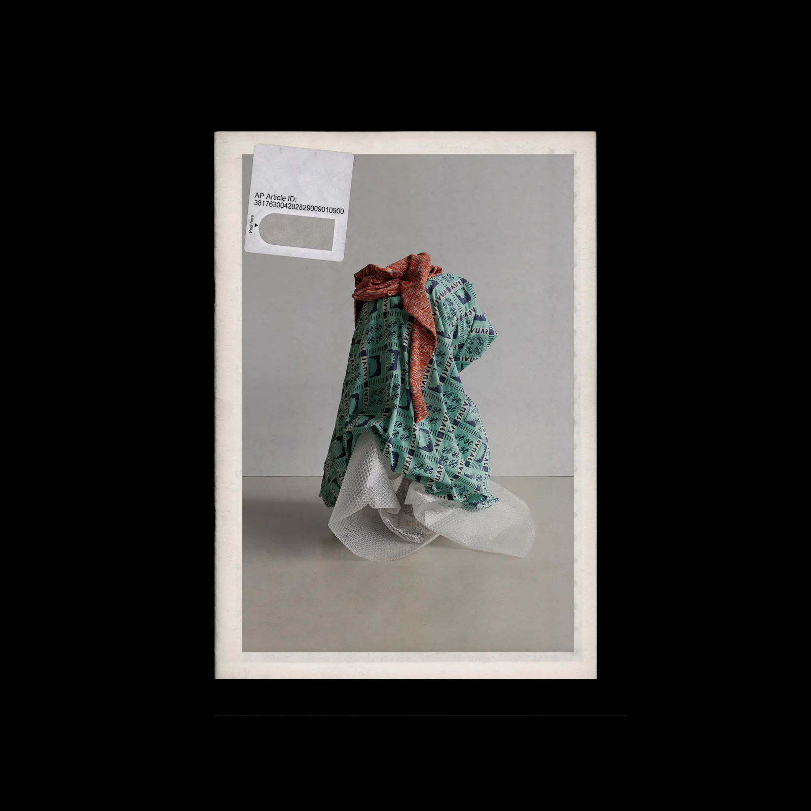 Creative direction for Other Boundaries by fashion label Kloke. A framed photographic print, set against a black background, shows a soft sculptural arrangement of teal patterned and sheer white fabric, with a small graphic label in the upper corner. U-P(co)2010