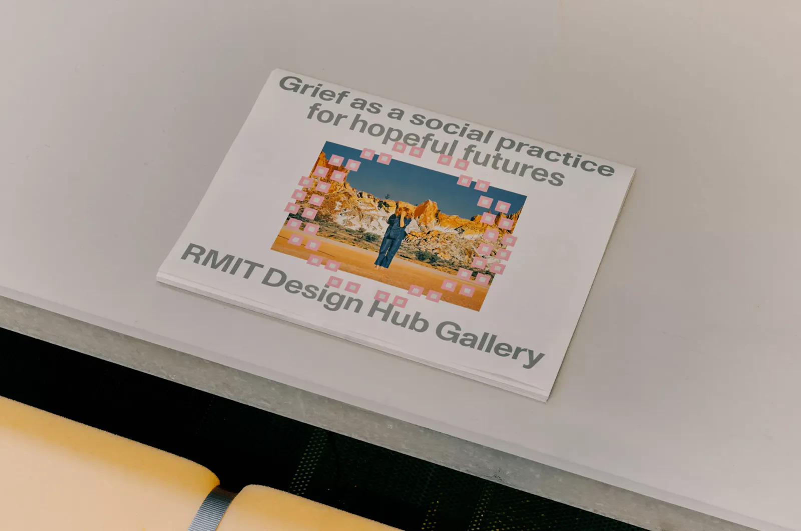 Detail of printed publication material from The Mourning After at RMIT Design Hub. A booklet or panel displays the title "Grief as a social practice for hopeful futures" above a desert landscape image, with "RMIT Design Hub Gallery" set in arched lettering. U-P(co)2010