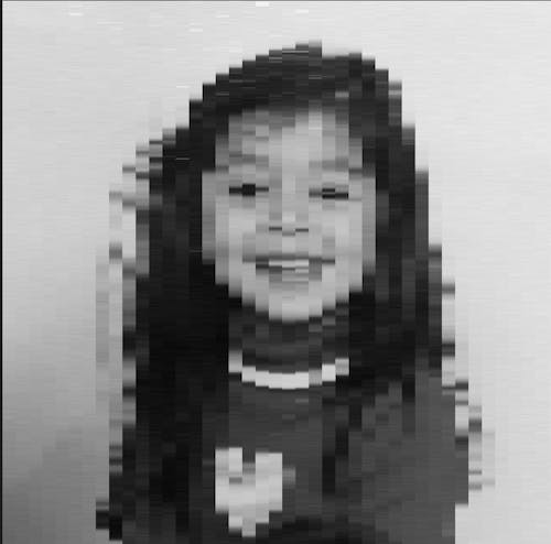 Black and white, grayscale pixelated portrait of child with turtleneck sweater and long black string their, smiling with teeth, 