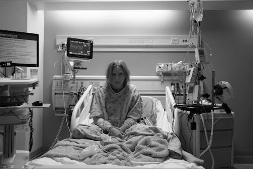 white woman in hospital bed staring at the camera. Black and white image