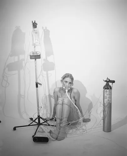 black and white image of white woman in underwear. She is covered in oxygen tubing with a bi pap mask on her face.