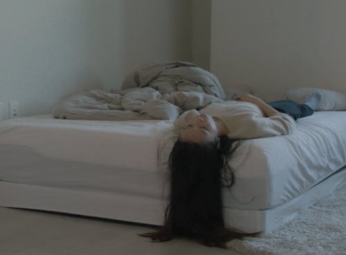 A girl lying on the bed, and the room is messy.