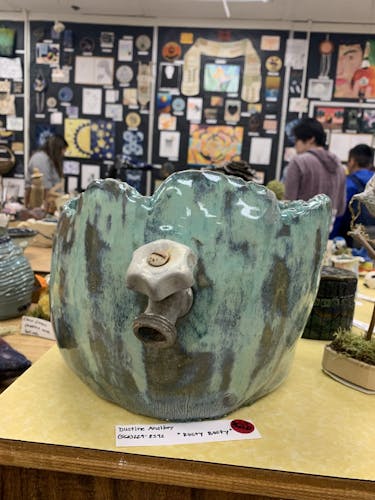 Mixed jade glazed bust of stomach with rusted faucet coming out of belly button, inside is melted blue and green glass