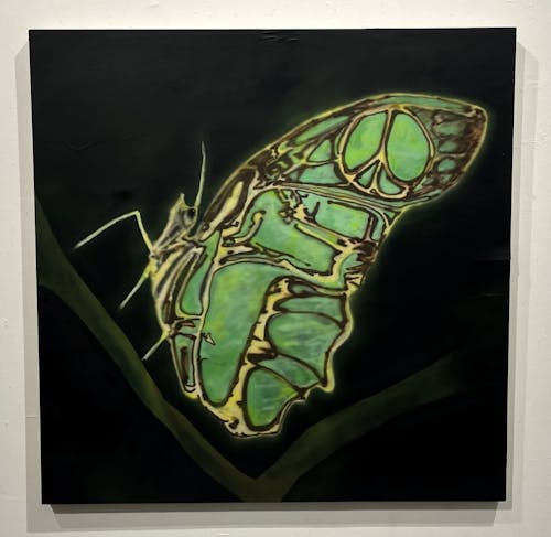 A square wood panel with a black background, an airbrush painted image of a mint-green butterfly stands atop a V shaped blade of green grass. the patterns of dark umber stripe on the butterfly's wings form a peace sign toward the top corner of its wing.