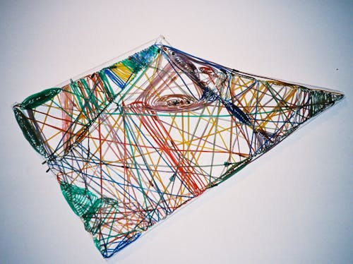 3-d triangular white framed sculpture with bright colored oxygen tubes wrapped around in all directions. 