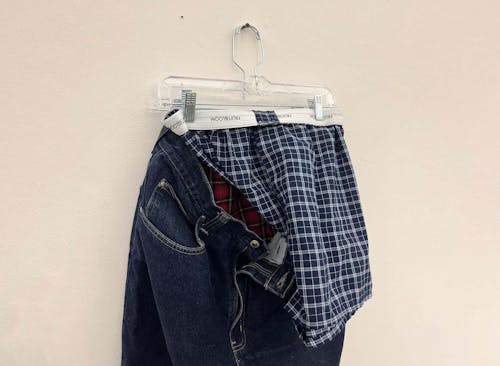  My blue jeans hang on a screw alongside two of my boxer briefs. The pants are not zipped so that both boxers can be visible, yet one is slightly hidden. The red briefs can’t be seen as they are hung to fit inside my pants. The blue plaid boxers hanging on a different hanger, lay haphazardly on the outside of the pants, allowing the viewer to faintly see the zipper, button, and red boxers.