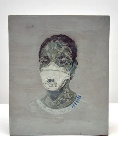 In the center of a light grey glazed rectangular ceramic slab is a clay inlay portrait of a woman with tied-up brown hair and a white collared shirt, wearing a white 3M Aura N95 Respirator mask with blue straps. The woman, who is depicted neck-up, is turning her head slightly to stare at the viewer.