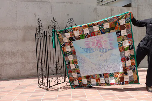 Lost Angelenos is a narrative quilt made by Makeda. She expresses her love and disdain for the City of Los Angeles through a quilt that includes writings and a central painting with flying angels.