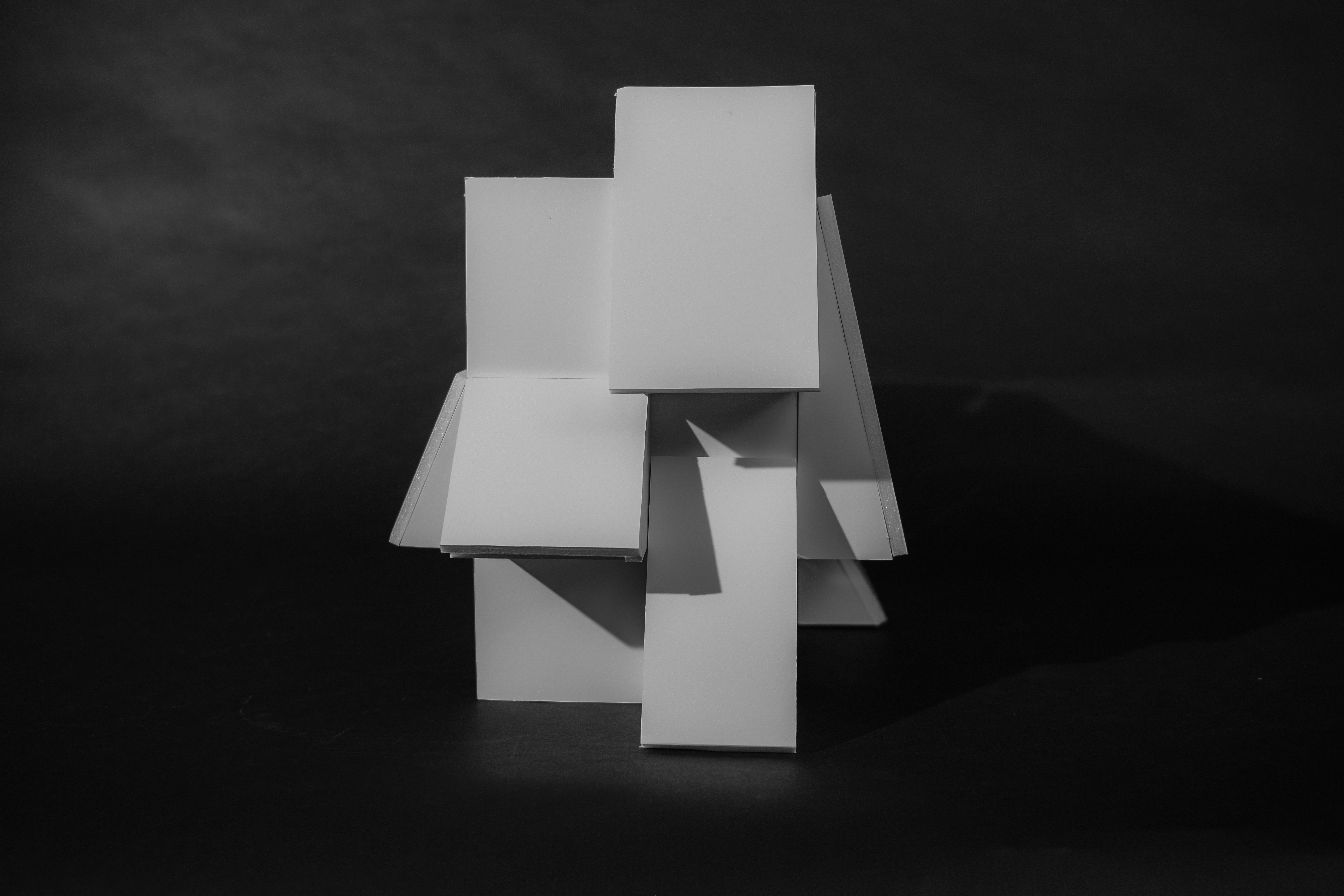 White foamcore model of a building on a black background.