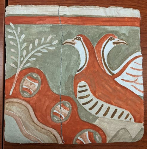 A fresco wall painting of two birds facing different directions next to three eggs and two branches of leaves. The painting is muted reds, browns, greens, and cream. There is a crack down the center of the wall painting. 