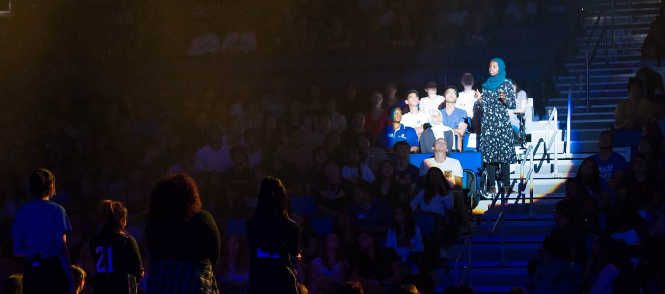 A spotlight on a person in the audience of a large auditorium.