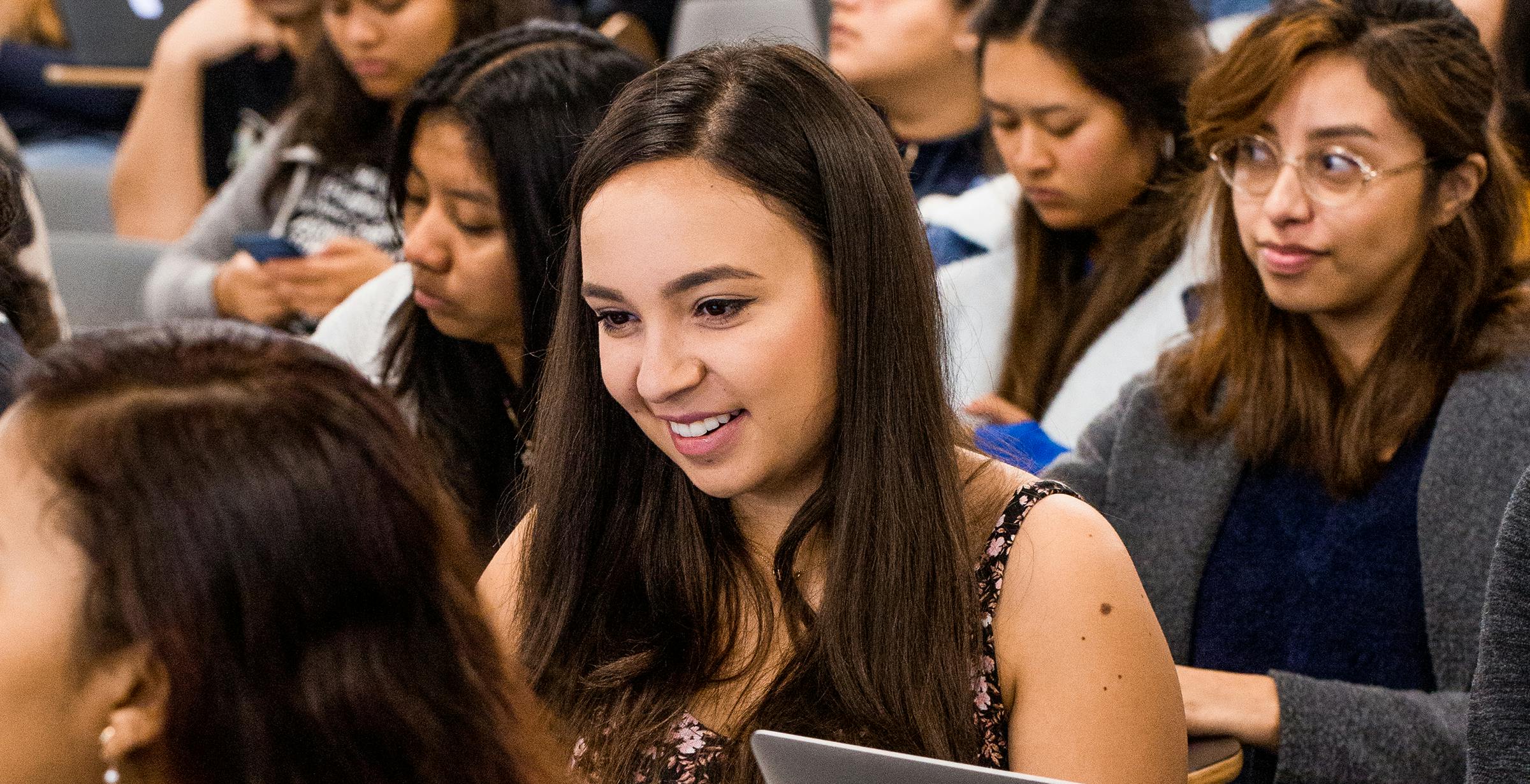 Female student smiling in class looking at laptop