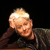 Susan Leigh Foster, a white woman with short, spiky white hair, leans her head on the palm of her right hand, with a bemused expression on her face.