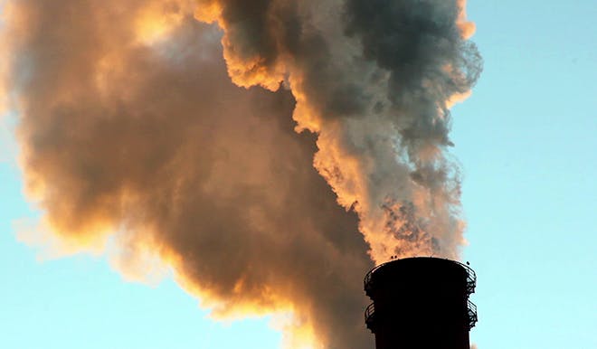 Industrial pollution billows from a smokestack.