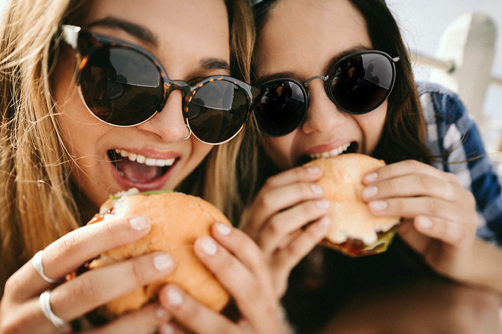 Two young women enjoy burgers.