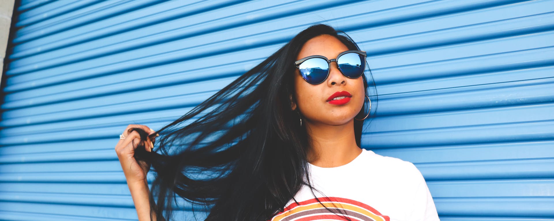 Girl playing with her hair in front of a blue garage door