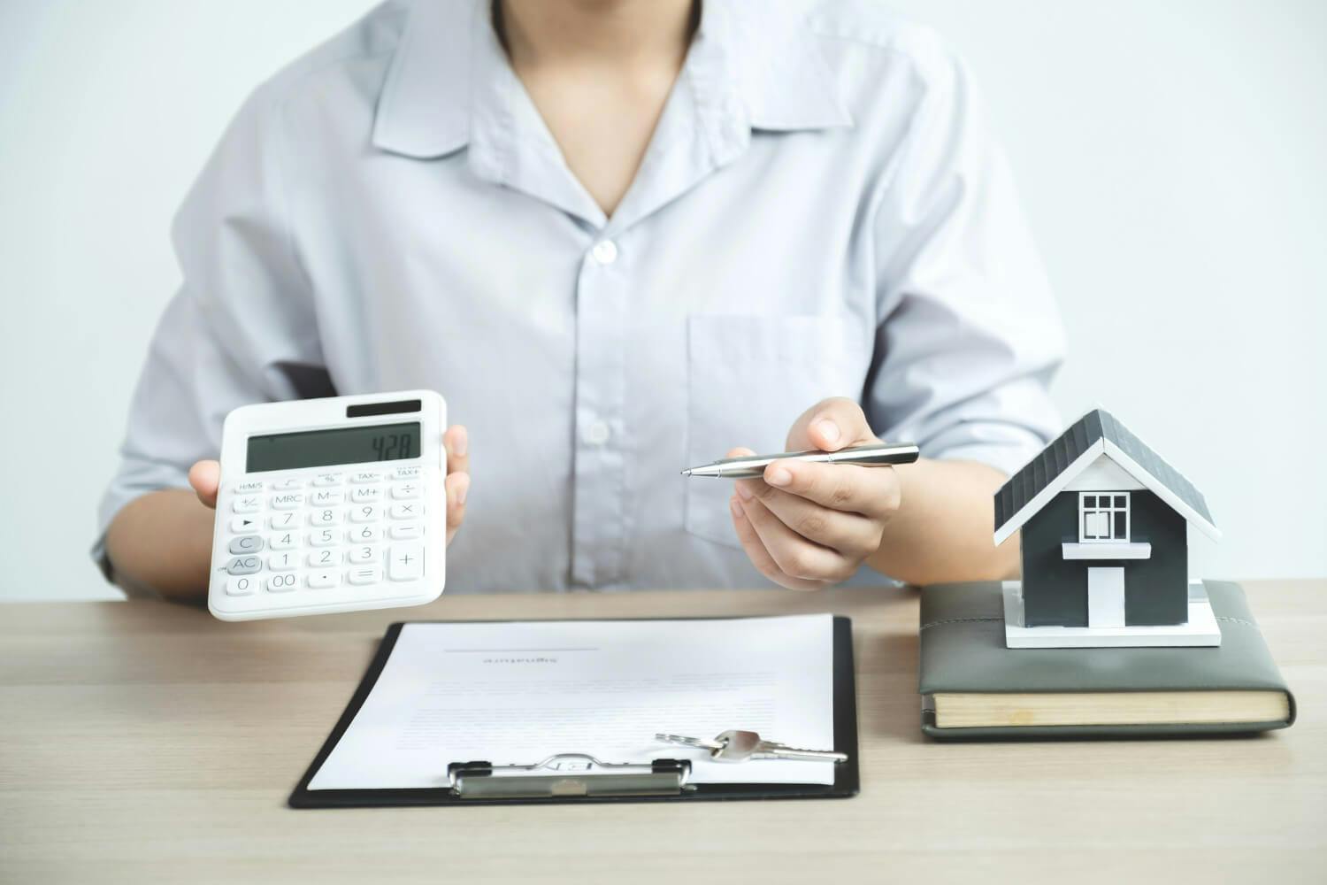 person holding calculator and pen over contract