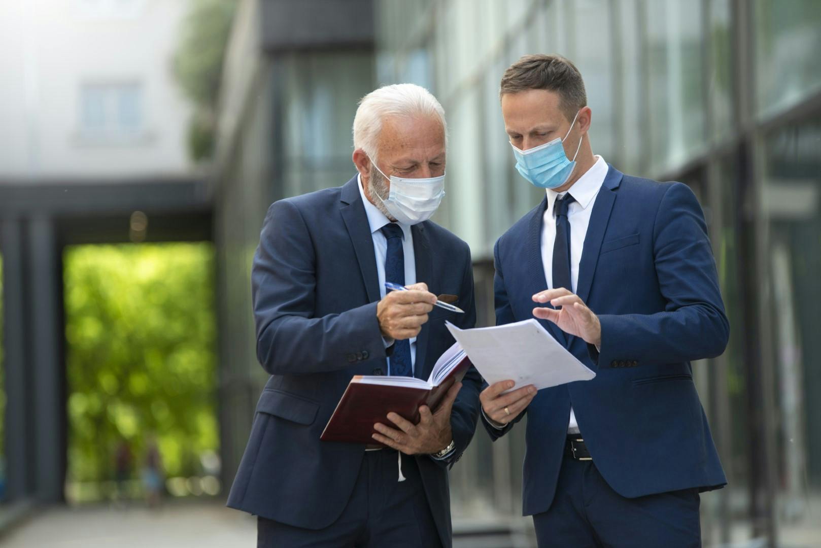 2 men in suits outside offices with face coverings