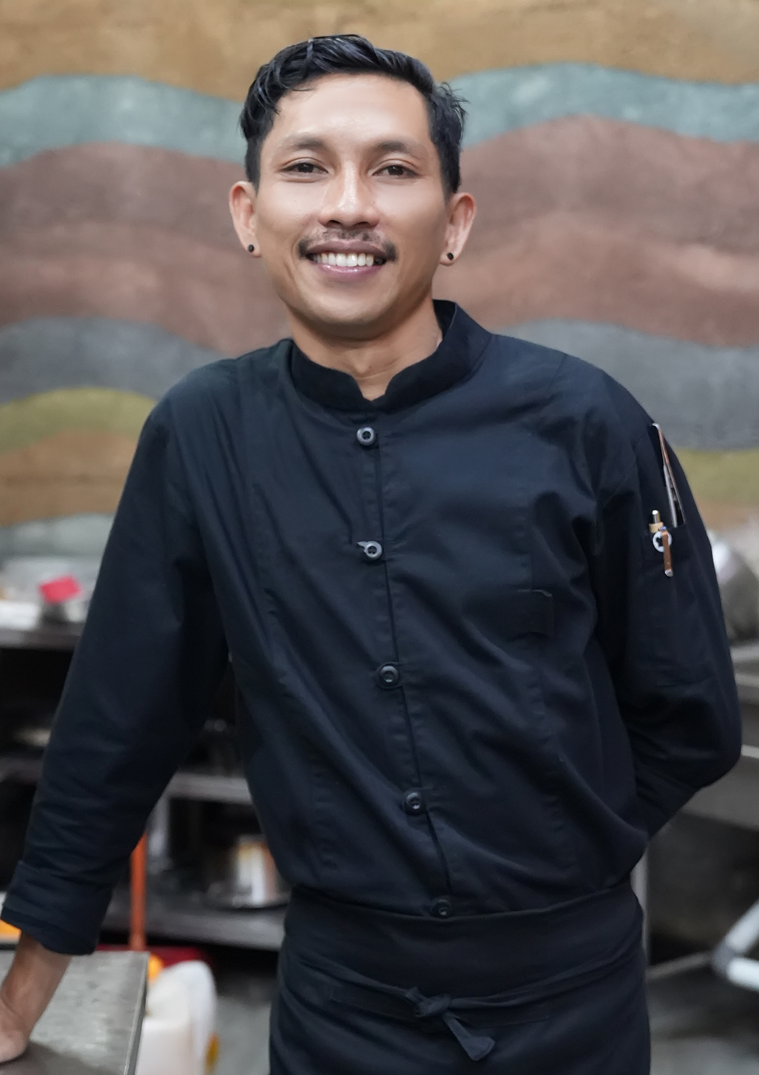 Smiling chef Alvin in a black uniform at Ulaman Eco Luxury Resort.