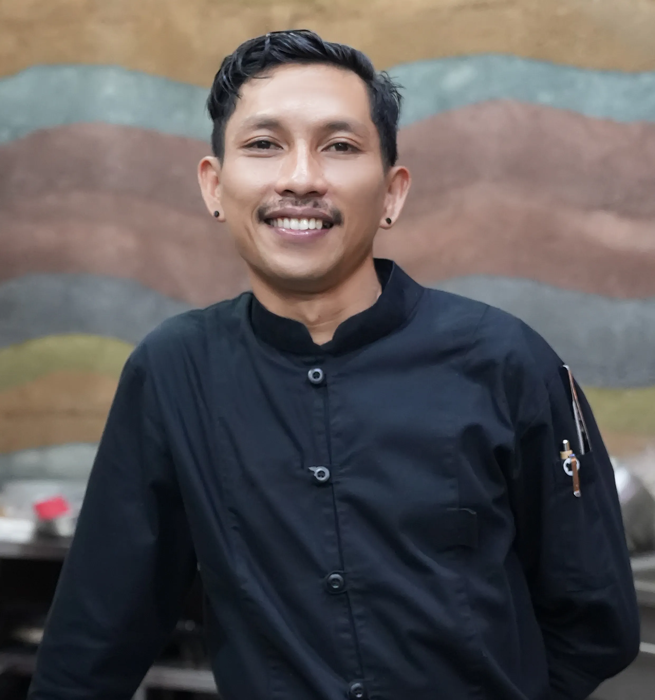 Smiling chef Alvin in a black uniform at Ulaman Eco Luxury Resort.