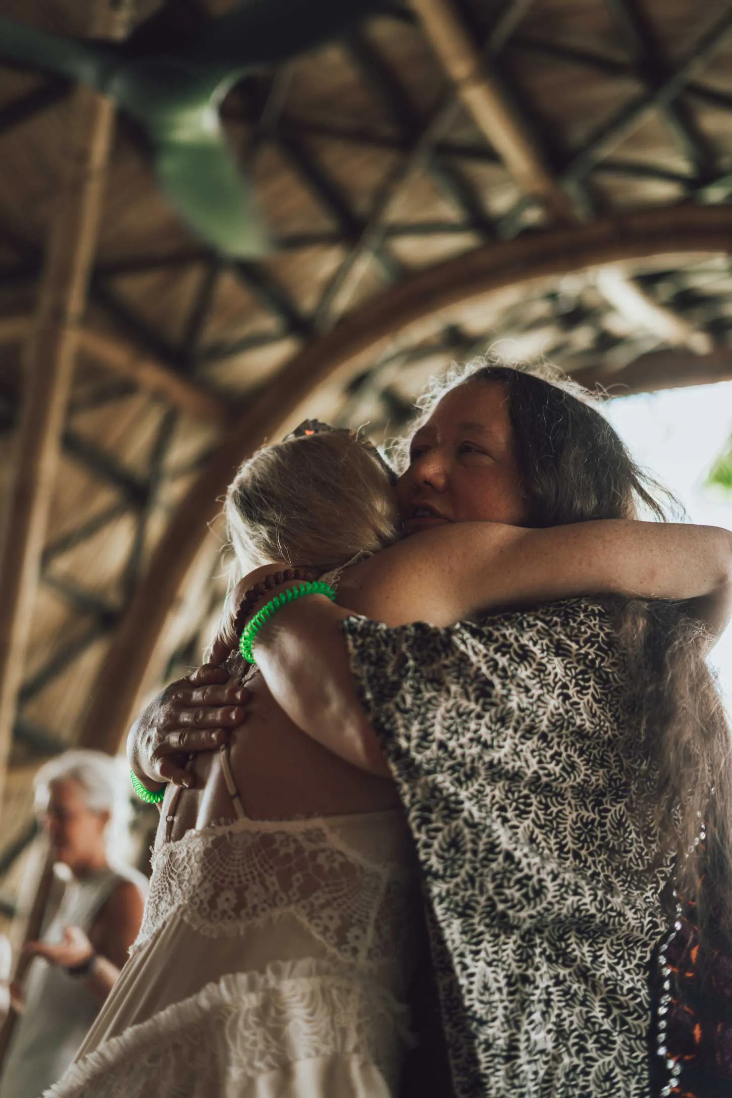 Two women sharing a heartfelt embrace inside a beautiful bamboo shala venue in Bali during an emotional wellness retreat experience