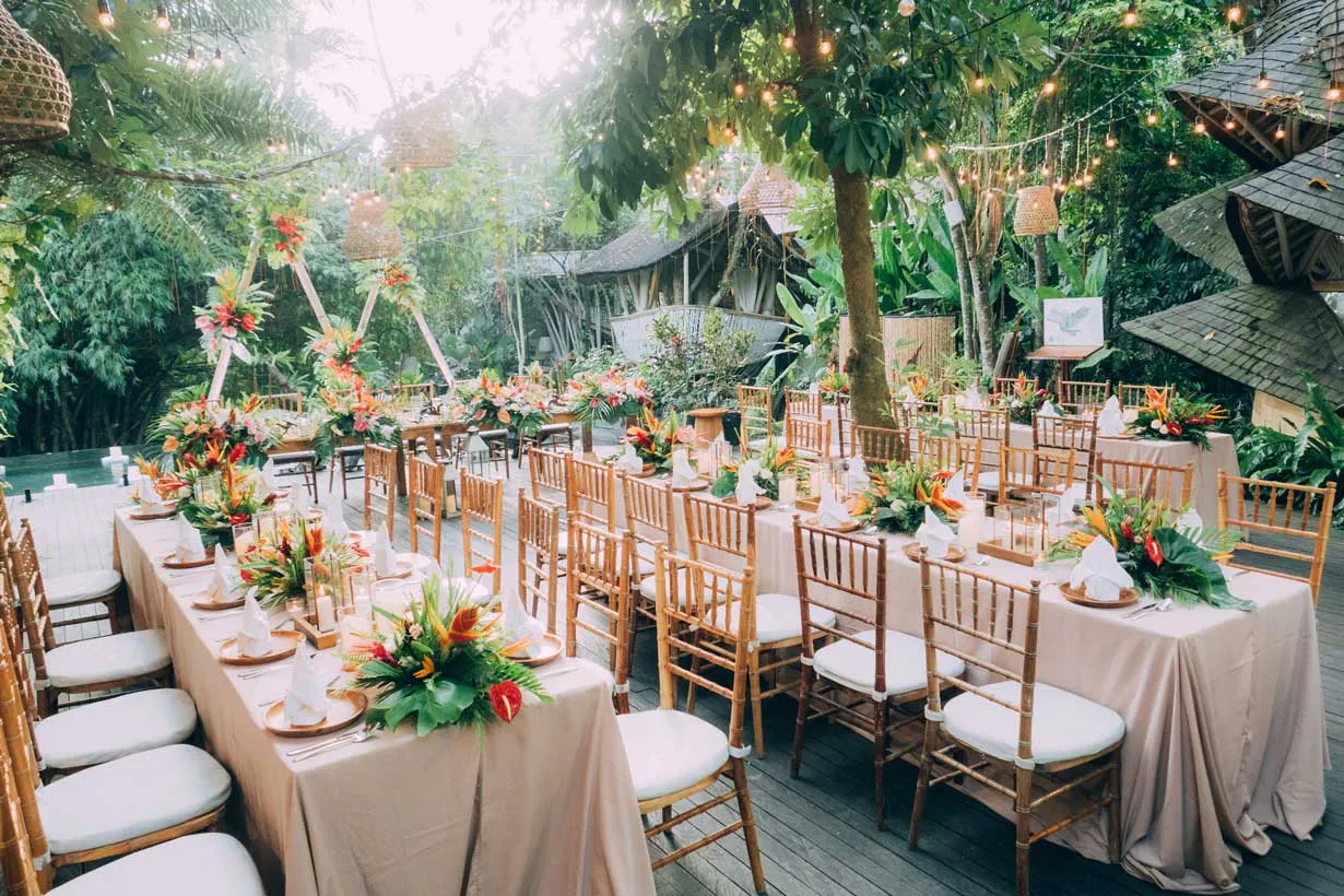 Lush tropical wedding reception setup with chiavari chairs, floral centerpieces, and string lights at an open-air Bali venue