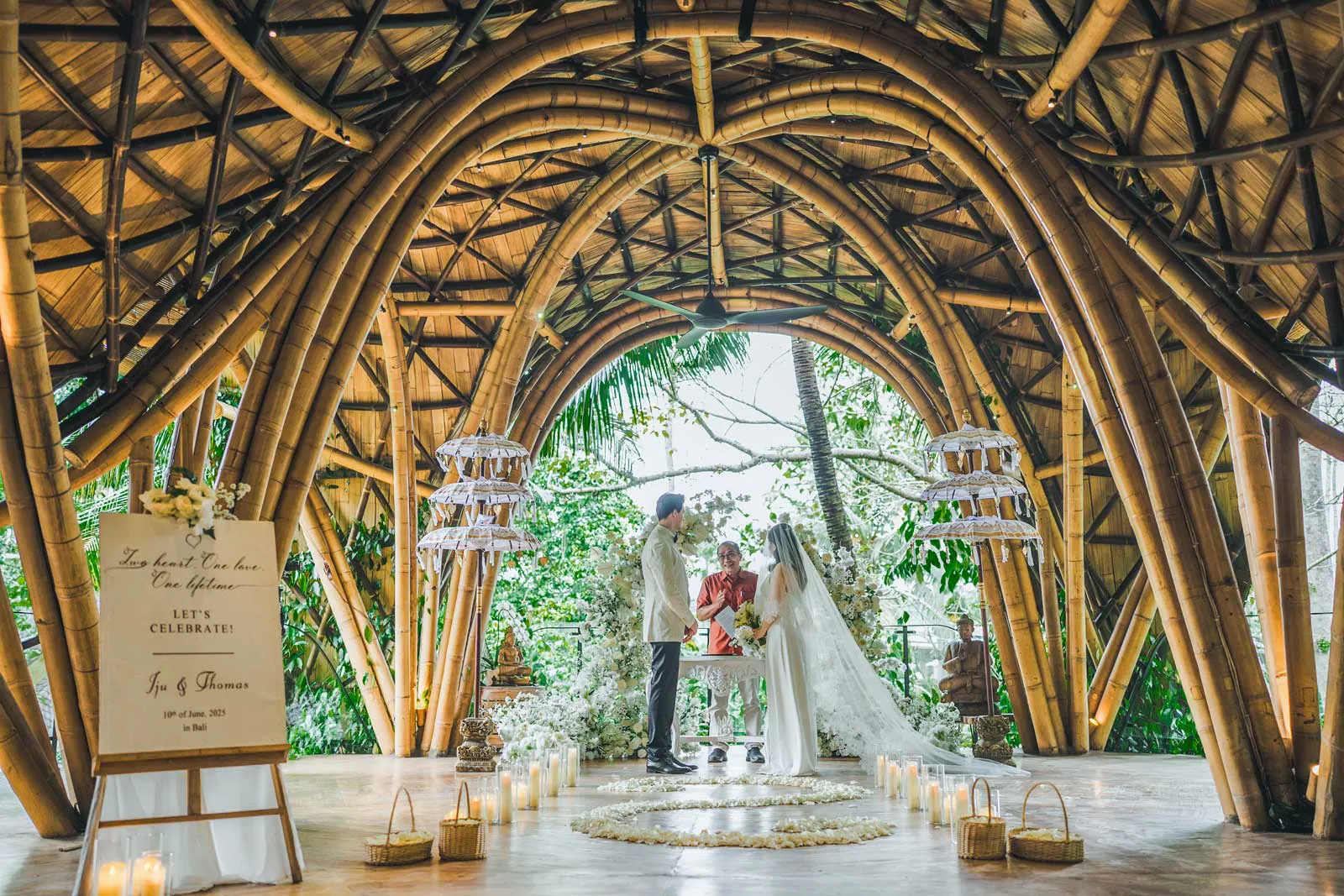 Couple exchanging vows inside a stunning arched bamboo wedding chapel during their destination wedding in Bali