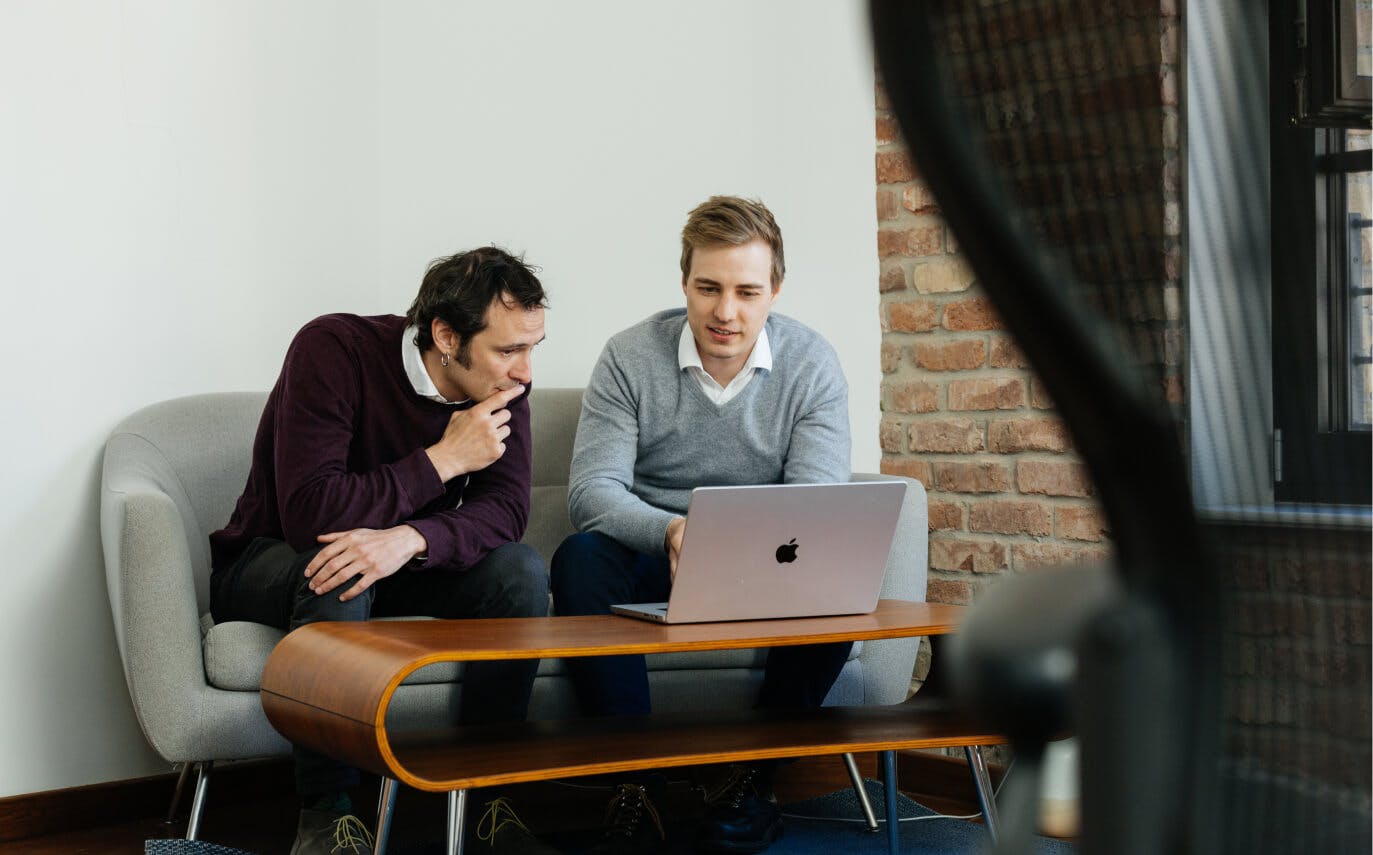 Der Ingenieur für Software Dr. Anton Daneyko bespricht die Inhalte eines Laptops mit dem Quantitativem Investment Analysten Dr. Thilo Kind.